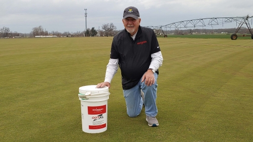 Richard Hurley GSNB’83 at the East Coast Sod & Feed farm in Salem County, New Jersey, with a bucket of turfgrass seed he developed.